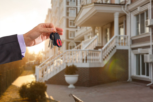 Держать ключи от дома на брелке в форме дома перед новым домом - Фото, изображение