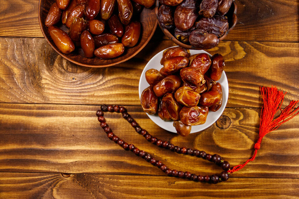 Fechas fruta y rosario en mesa de madera. Vista superior. La fiesta musulmana del mes sagrado del Ramadán - Foto, imagen