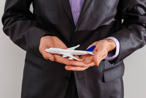 Adult businessman in suit holding a plane isolated on white - Photo, Image