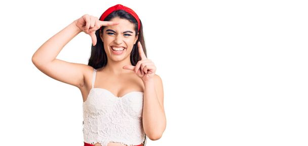 Брюнетка девушка подросток носить элегантный вид улыбаясь делая рамку с руками и пальцами с счастливым лицом. креативность и концепция фотографии.  - Фото, изображение