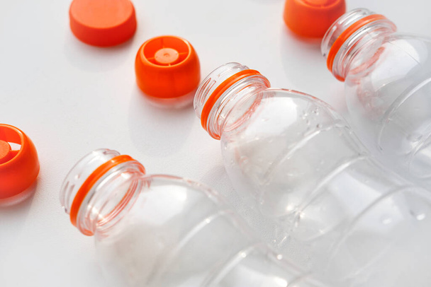 Plastic bottles with orange caps for recycling lie on a white table. Concept of Recycling plastic and ecology. Plastic waste. Stop nature garbage - Foto, Imagem