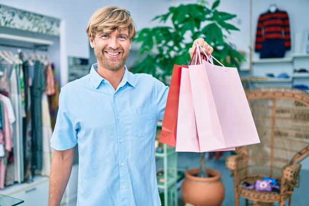ショッピングセンターの小売店で幸せなショッピングを笑顔でハンサムな白人男性 - 写真・画像