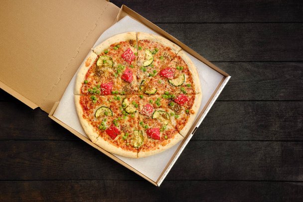 Pizza with beef, zucchini, bell pepper and green pea in take away packaging - Fotó, kép