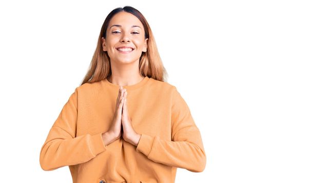 Beautiful young woman wearing casual clothes praying with hands together asking for forgiveness smiling confident.  - Foto, immagini