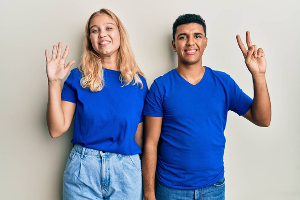Young interracial couple wearing casual clothes showing and pointing up with fingers number seven while smiling confident and happy.  - Foto, Imagem