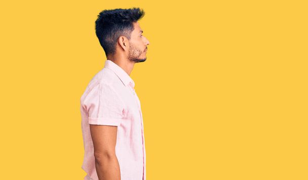 Hombre joven latinoamericano guapo con camisa de verano casual mirando al costado, pose de perfil relajado con cara natural y sonrisa confiada.  - Foto, Imagen