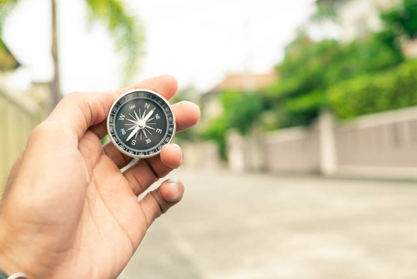 Man hand holding compass on city and car blurred background Using wallpaper or background travel or navigator image. - Photo, Image