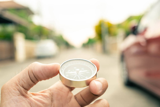 Чоловік тримає компас на міському та автомобільному розмитому фоні Використовуючи шпалери або фонові подорожі або зображення навігатора
. - Фото, зображення