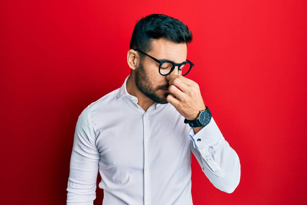 Jonge Spaanse zakenman draagt shirt en bril moe wrijven neus en ogen gevoel vermoeidheid en hoofdpijn. stress en frustratie concept.  - Foto, afbeelding