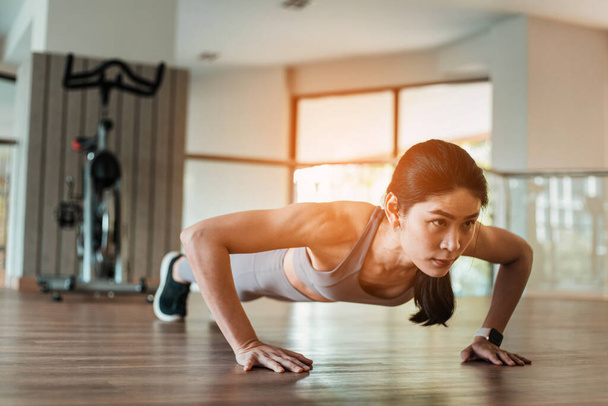 Beautiful young Asian woman doing push ups in the gym - Фото, изображение