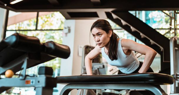 Young Beautiful Asian Woman doing push-up exercise on the bench - Photo, Image