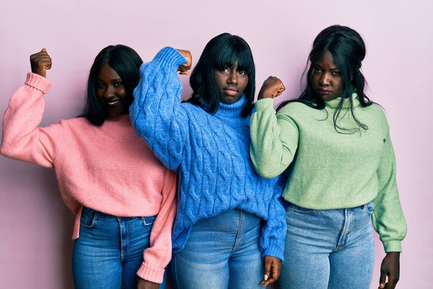 Τρεις νεαροί Αφροαμερικανοί φίλοι που φορούσαν μάλλινο χειμωνιάτικο πουλόβερ, δυνατό άτομο που έδειχνε μπράτσα, αυτοπεποίθηση και περηφάνια για την εξουσία.  - Φωτογραφία, εικόνα