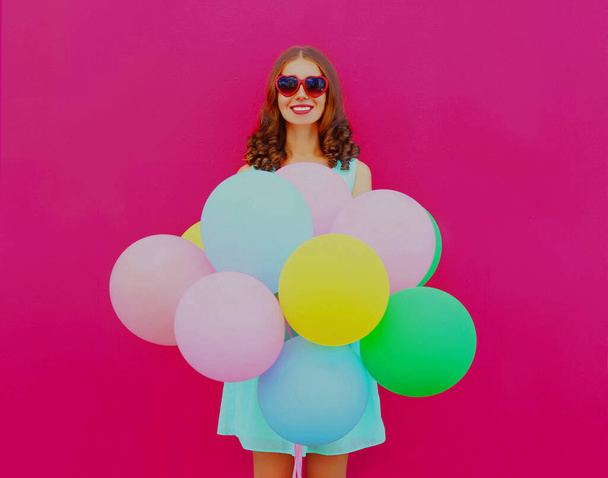 Happy smiling young woman with colorful balloons on a pink background - Fotoğraf, Görsel