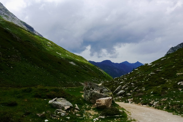 Yeşil dağlarda yürüyüş yaparken toprak bir yolun yakınındaki büyük kayalar. - Fotoğraf, Görsel