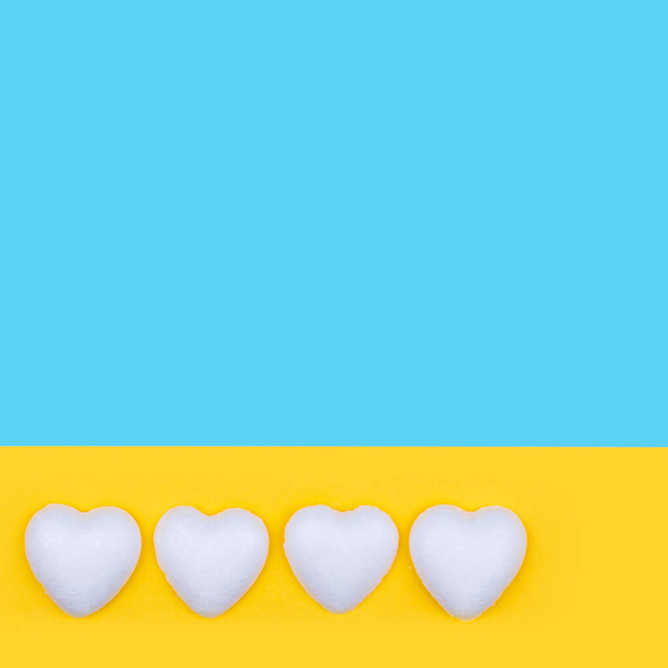 Corazones blancos sobre fondo amarillo y azul. Composición mínima del espacio de copia del día de San Valentín. - Foto, imagen