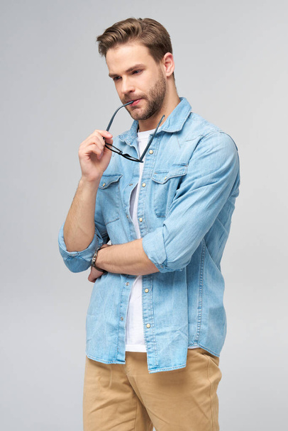 Portrait of young handsome caucasian man in jeans shirt over light background - Foto, Imagem