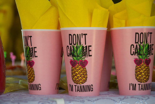 Vasos de plástico con texto "No me llames, estoy bronceándome", con servilletas amarillas, concepto de fiesta, celebración, fiesta temática tropical - Foto, Imagen
