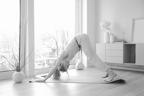 Giovane bella donna che pratica yoga posa vicino a grande finestra - Foto, immagini