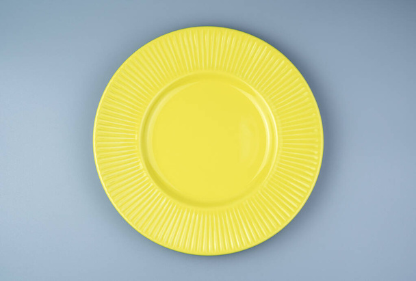 An empty yellow plate on a gray background. - Photo, Image