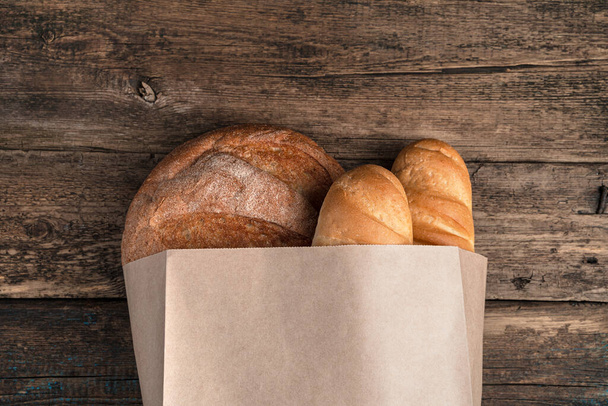 Bread in a bag on a wooden background. Top view, with space to copy. - Fotoğraf, Görsel