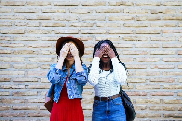 Dvě kamarádky si venku zakryjí oči. Multietnické ženy. - Fotografie, Obrázek