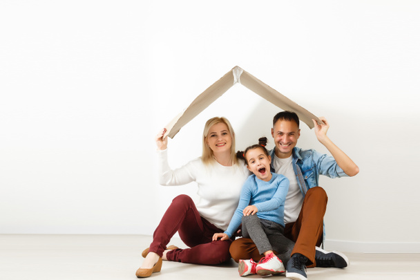 Happy family sitting on wooden floor. Father, mother and child having fun together. Moving house day, new home and design interior concept - Photo, Image