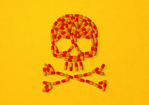 Skull made of orange capsule pills isolated on yellow background. 3D illustration - Φωτογραφία, εικόνα