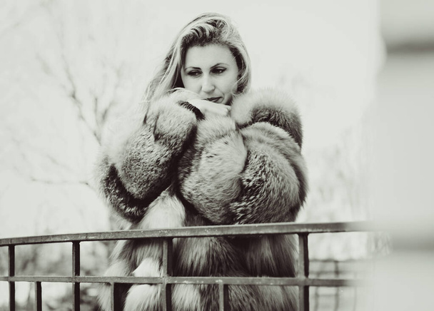 Stylish lady in a vintage style of clothes. She is dressed in a velvet dress and a light red fur coat. Style 50s in modern life - Zdjęcie, obraz