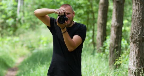 Hombre fotógrafo tomar una foto con una cámara profesional al aire libre - Imágenes, Vídeo