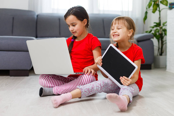 Dos niñas están jugando con el ordenador portátil en la sala de juegos en casa - Foto, Imagen