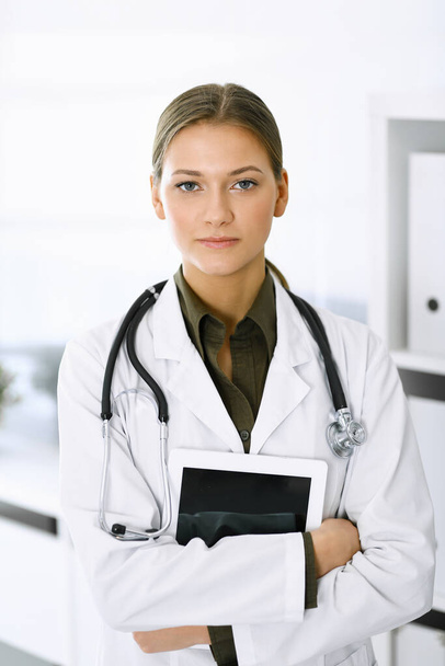 Woman-doctor standing and looking at camera. Perfect medical service in clinic. Medicine and healthcare - Фото, зображення