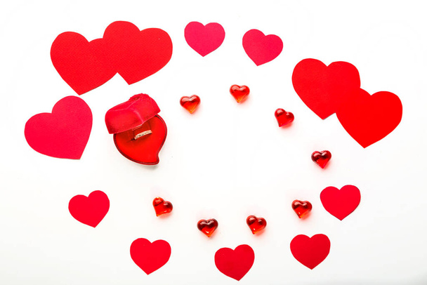 Red hearts from paper of different sizes for Valentine's day and glass hearts and a velvet box in the shape of a heart with a ring on a white background. Horizontal photo - Photo, Image