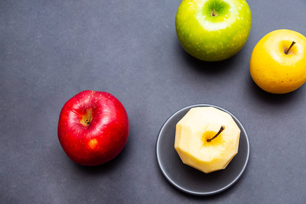 Appels groen, geel, rood en appel zonder schil op een zwarte achtergrond. Gezond voedselconcept met kopieerruimte - Foto, afbeelding
