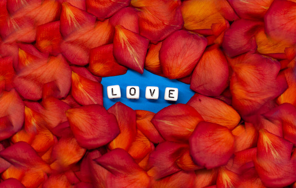 Het woord liefde op de achtergrond van rozenblaadjes. Valentijnsdag. Achtergrond concept van liefde en schoonheid - Foto, afbeelding