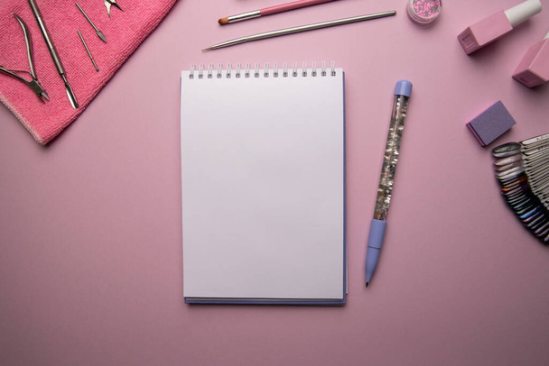 Top view of open empty spiral notebook with pen and manicure accessories on pink background,flat lay - Foto, afbeelding