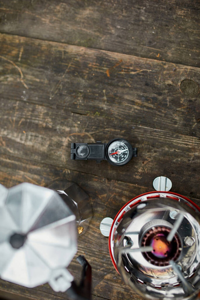 Kompassi, kaasupoltin, kahvinkeitin puupöydällä ulkona, Retkeilyvarusteet - Valokuva, kuva