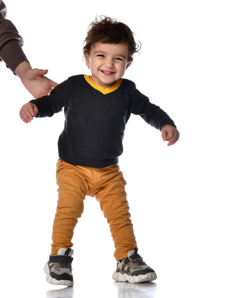 Happy little kid boy learning to walk standing on two legs against white background in studio. - Foto, imagen