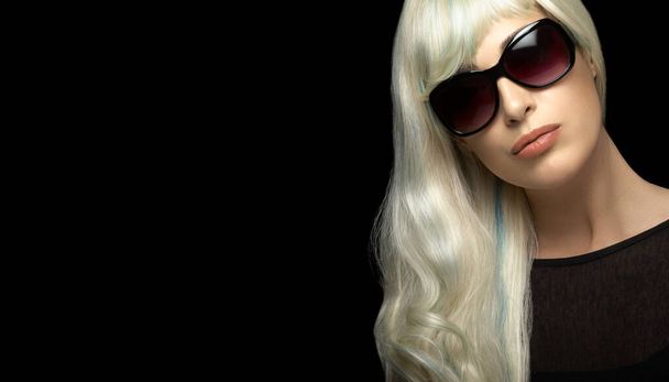 Retrato de moda de uma mulher loira atraente com cabelos brancos prateados longos saudáveis, usando óculos escuros pretos, olhando para a câmera. Close-up isolado em fundo preto com espaço de cópia para texto - Foto, Imagem