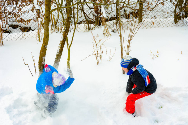 İki çocuk kartopu oynuyor, kışın eğlenceli bir oyun, çocuklar için mutlu bir çocukluk. 2021 - Fotoğraf, Görsel