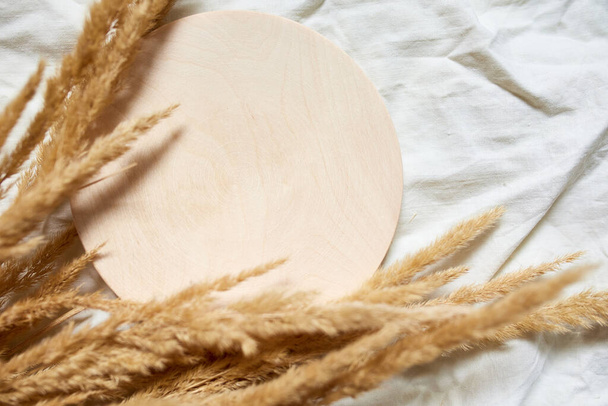 Flat lay of beige reeds pampas grass on the white textile linen tablecloth background, beautiful pattern with neutral colors, Minimal, stylish, trend concept, top view - Photo, Image