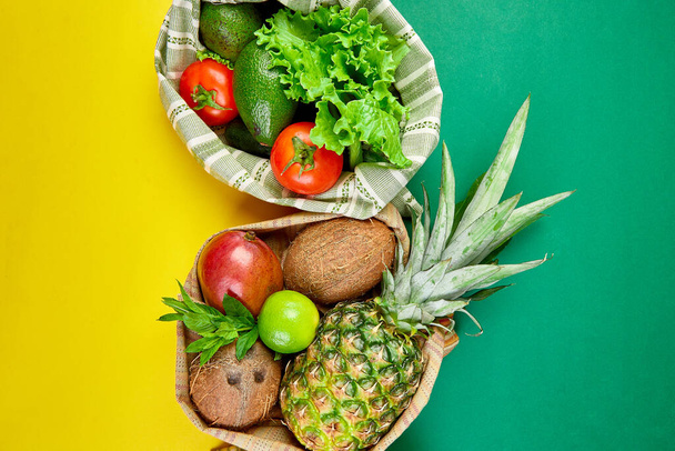 Επίπεδη lay του οικολογικού παντοπωλείο ψώνια τσάντες βαμβάκι με βιολογικά φρούτα και λαχανικά σε κίτρινο πράσινο φόντο. Μηδέν απόβλητα, πλαστικό ελεύθερο τρόπο ζωής έννοια. Υγιή χορτοφαγική διατροφή και αποτοξίνωση. - Φωτογραφία, εικόνα