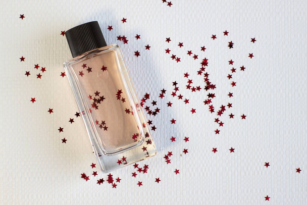Beautiful bottle of perfume on a cozy knitted textured background with sparkles close-up - Photo, Image