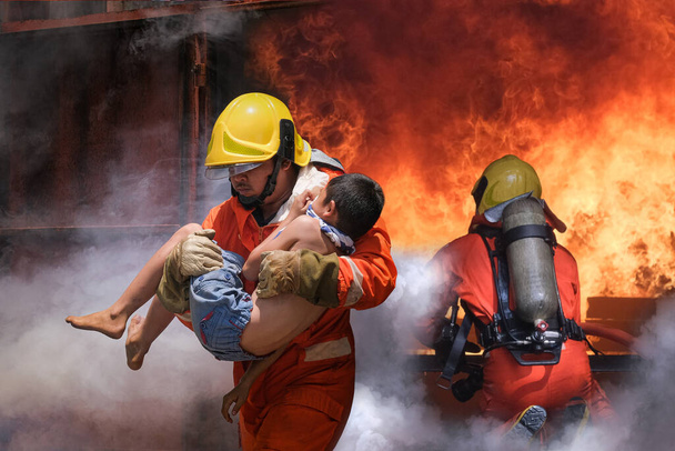 Bombero sosteniendo niño niño para salvarlo en el fuego y el humo, Bomberos rescatar a los niños del fuego. - Foto, imagen