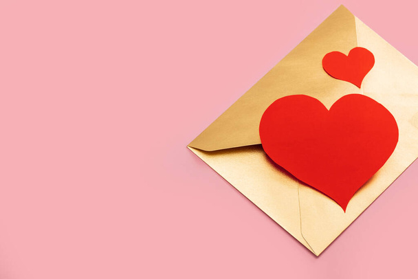 Golden paper envelope with two red hearts isolated on pink background - Foto, Bild