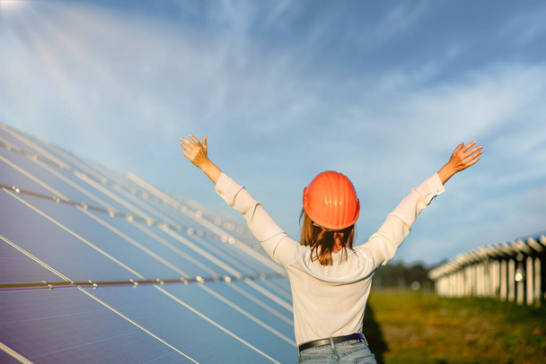 Beautiful young engineer standing near solar panels outdoors, Green Energy Concept. - Φωτογραφία, εικόνα