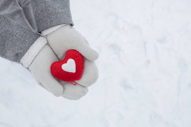 hands in white knitted gloves hold a red heart - a symbol of love and happiness, February 14 Valentine's Day - Foto, afbeelding