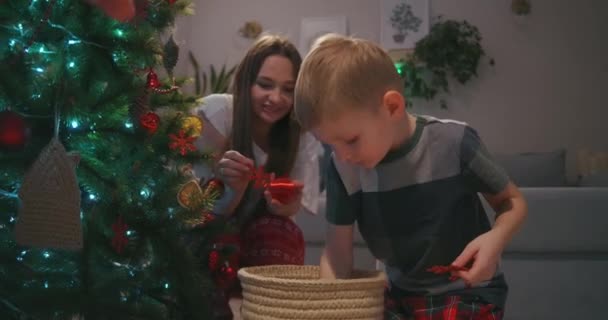 Der Junge sucht sich Glaskugeln für seine Mutter aus, um den Weihnachtsbaum zu schmücken. Familie schmückt gemeinsam Haus zu Weihnachten - Filmmaterial, Video