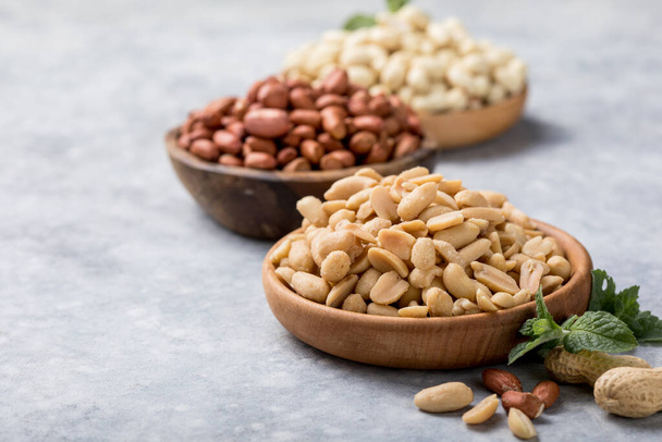 Roasted salted peanuts. Crispy nuts in bowl on stone table. - 写真・画像
