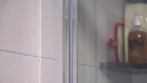 シャワースクリーンを絶縁するときにそれをオフに終了するシリコーンコードを指を実行している男の4kビデオ - 映像、動画