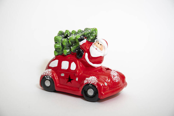Miniatyyri punainen auto kuljettaa joulukuusi ja lahjoja. Tekstiavaruus. Kausiluonteinen tervehdys. Hyvää joulua. - Valokuva, kuva
